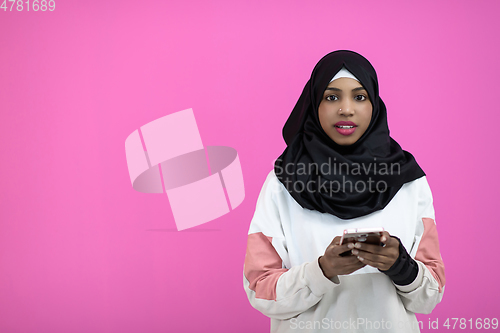 Image of afro woman uses a cell phone in front of a pink background