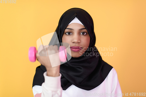 Image of afro muslim woman promotes a healthy life, holding dumbbells in her hands