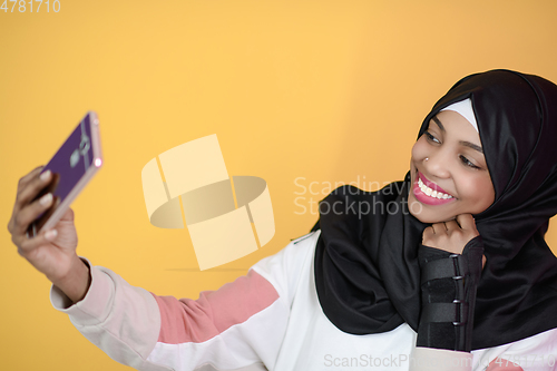 Image of african muslim woman with a beautiful smile takes a selfie with a cell phone