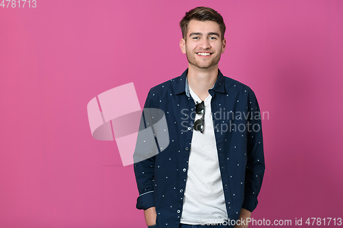 Image of a portrait of a young man wearing a blue shirt and posing in front of a pink background 