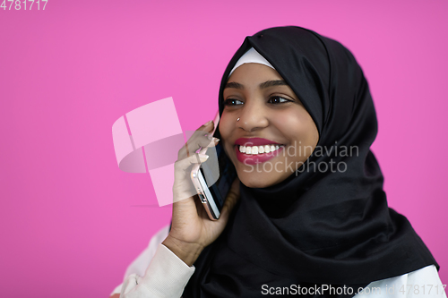 Image of afro woman uses a cell phone in front of a pink background