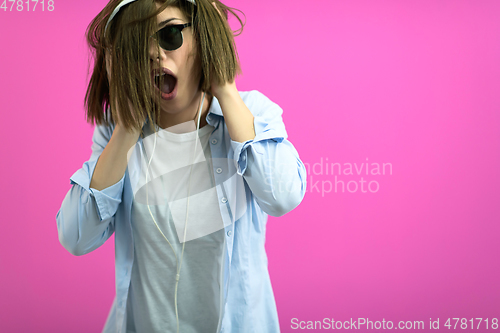 Image of brunette lady in black glasses dancing and listening music isolate on pink background