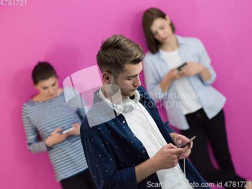 Image of group of diverse teenagers use mobile devices while posing for studio photo