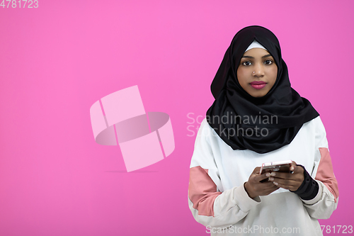 Image of afro woman uses a cell phone in front of a pink background