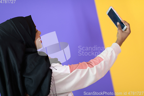 Image of african muslim woman with a beautiful smile takes a selfie with a cell phone