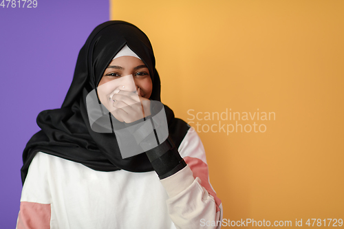 Image of African Muslim woman wearing hijab and traditional Muslim clothes posing in front of yellow background