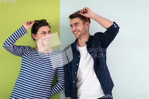Image of Beautiful young loving couple adjusting their sunglasses while standing against green-grey background