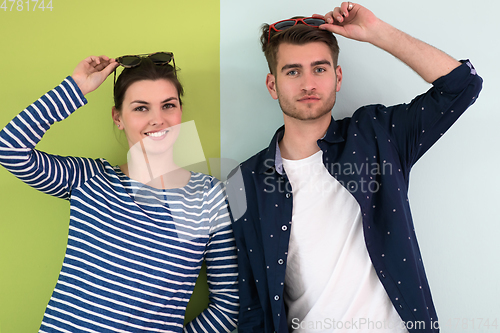 Image of Beautiful young loving couple adjusting their sunglasses while standing against green-grey background