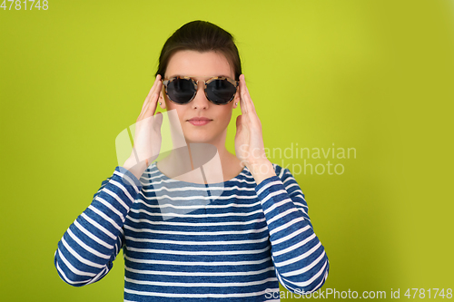 Image of woman in sunglasses posing in front of a green background