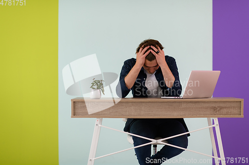 Image of disappointed and annoyed man sitting at a table and looking at a laptop