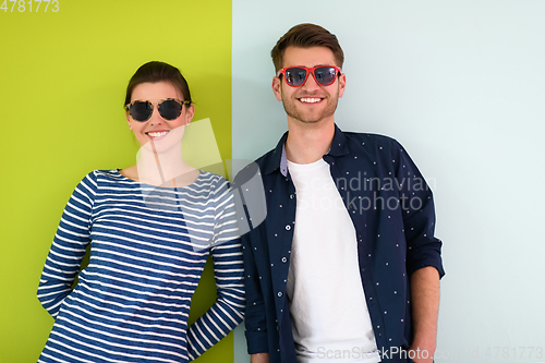 Image of Beautiful young loving couple adjusting their sunglasses while standing against green-grey background