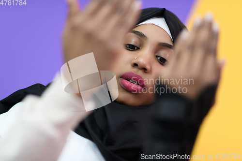 Image of african muslim woman wearing hijab and traditional muslim clothes posing in front of green background