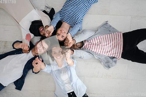 Image of top view of a diverse group of people lying on the floor and symbolizing togetherness