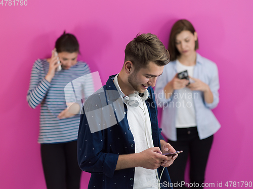 Image of group of diverse teenagers use mobile devices while posing for studio photo