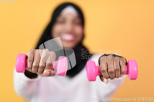 Image of afro muslim woman promotes a healthy life, holding dumbbells in her hands