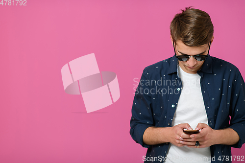 Image of a young man wearing a blue shirt and sunglasses using a smartphone