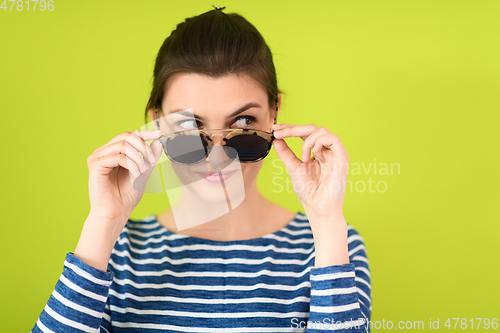 Image of woman in sunglasses posing in front of a green background