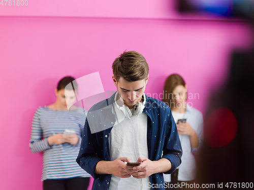 Image of group of diverse teenagers use mobile devices while posing for studio photo