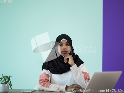 Image of afro girl wearing a hijab is disappointed and sad sitting in her home office and using a laptop