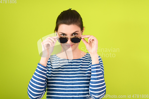 Image of woman in sunglasses posing in front of a green background