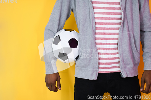 Image of afro man posing on a yellow background while holding a soccer ball