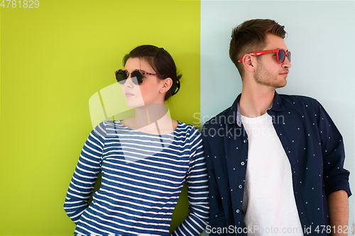 Image of Beautiful young loving couple adjusting their sunglasses while standing against green-grey background