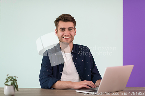 Image of Smiling young man freelancer using laptop studying online working from home