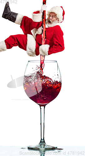 Image of Happy Christmas Santa Claus climbing on trickle of wine on white background