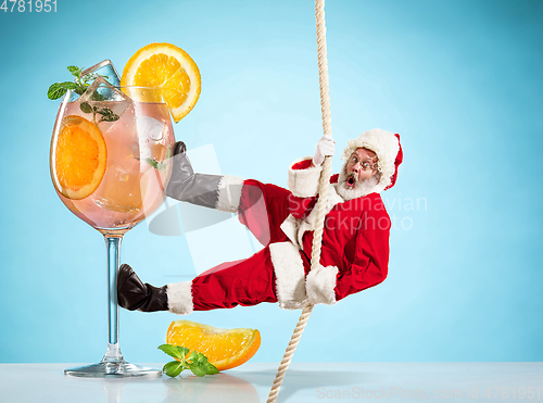 Image of Happy Christmas Santa Claus climbing on rope on blue background