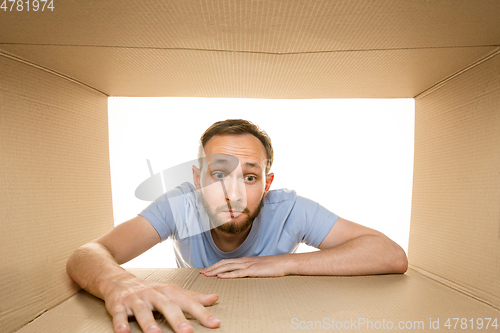 Image of Young man opening the biggest postal package isolated on white