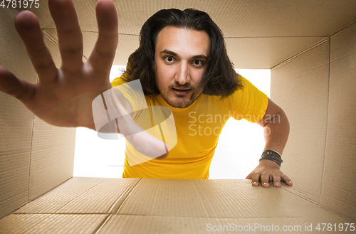 Image of Young man opening the biggest postal package isolated on white