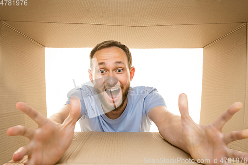 Image of Young man opening the biggest postal package isolated on white