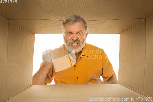 Image of Senior man opening the biggest postal package isolated on white