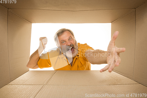 Image of Senior man opening the biggest postal package isolated on white