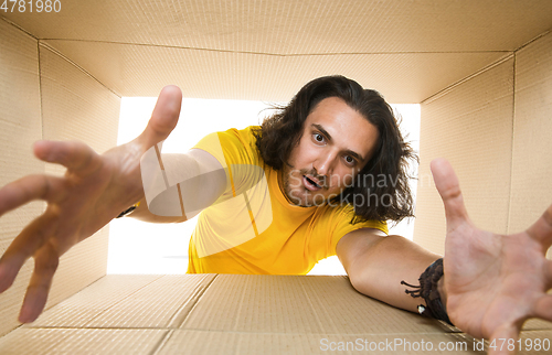 Image of Young man opening the biggest postal package isolated on white