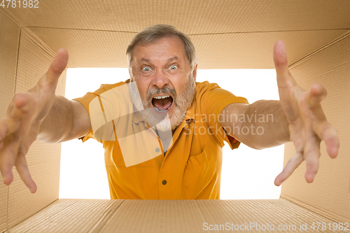 Image of Senior man opening the biggest postal package isolated on white