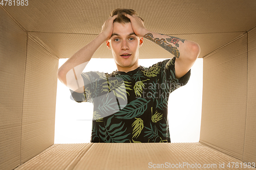 Image of Young man opening the biggest postal package isolated on white