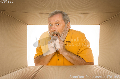 Image of Senior man opening the biggest postal package isolated on white