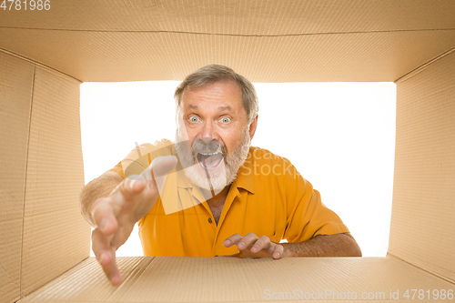 Image of Senior man opening the biggest postal package isolated on white