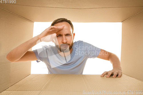 Image of Young man opening the biggest postal package isolated on white