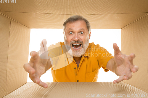 Image of Senior man opening the biggest postal package isolated on white