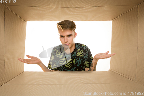 Image of Young man opening the biggest postal package isolated on white