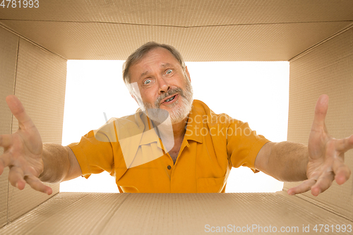 Image of Senior man opening the biggest postal package isolated on white