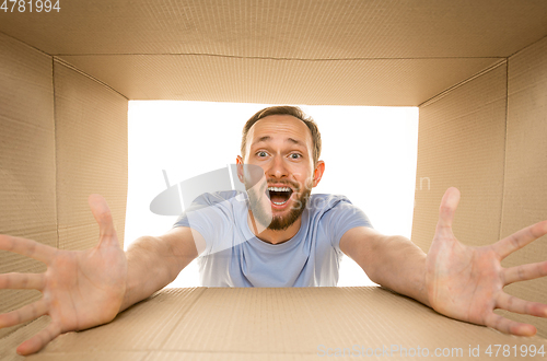 Image of Young man opening the biggest postal package isolated on white