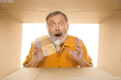 Image of Senior man opening the biggest postal package isolated on white