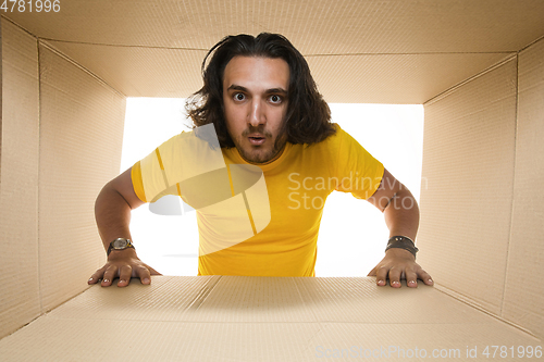 Image of Young man opening the biggest postal package isolated on white