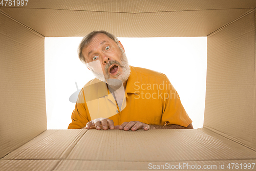 Image of Senior man opening the biggest postal package isolated on white