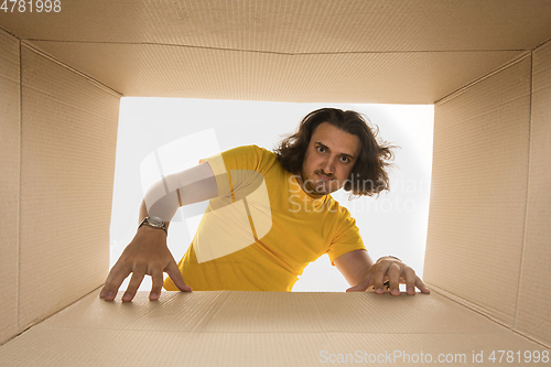 Image of Young man opening the biggest postal package isolated on white