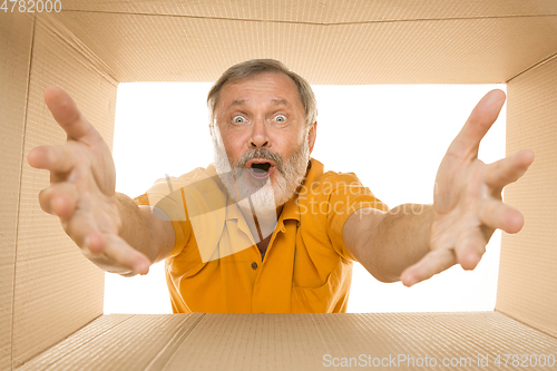 Image of Senior man opening the biggest postal package isolated on white
