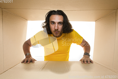 Image of Young man opening the biggest postal package isolated on white